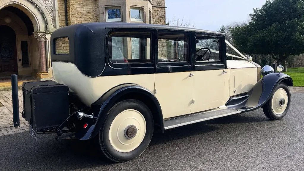 Rear right side view of vintage rolls-royce with black wheel arches and black picnic trunk at the rear of the vehicle