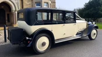 Rear right side view of vintage rolls-royce with black wheel arches and black picnic trunk at the rear of the vehicle