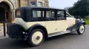 Rear right side view of vintage rolls-royce with black wheel arches and black picnic trunk at the rear of the vehicle