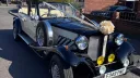 Front view of Vintage Beauford with a large Ivory bow on top of the Radiator