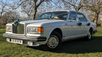 Quarter View of Classic White Bentley Muslanen parked in a green park decorated with Green Ribbons and Bows