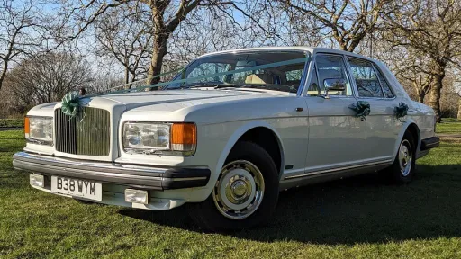 Quarter View of Classic White Bentley Muslanen parked in a green park decorated with Green Ribbons and Bows