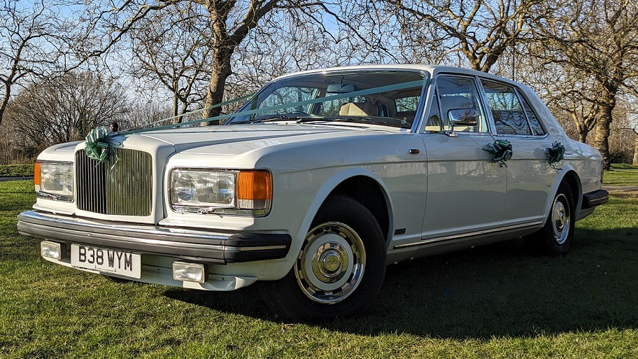Quarter View of Classic White Bentley Muslanen parked in a green park decorated with Green Ribbons and Bows