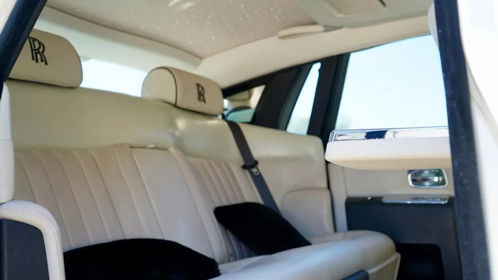 Rear interior seats inside Rolls-Royce Phantom. Cream leather seats with the RR logo emboided in the headrest.