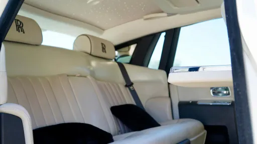 Rear interior seats inside Rolls-Royce Phantom. Cream leather seats with the RR logo emboided in the headrest.