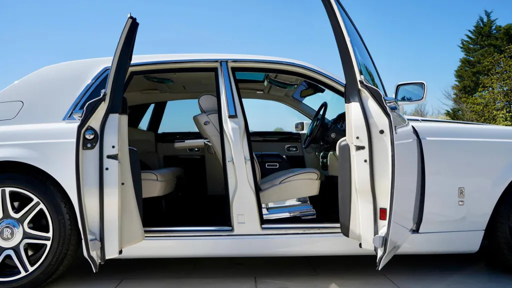 Right side view of White rolls-Royce Phantom with both front and rear coach doors open showing cream leather interior
