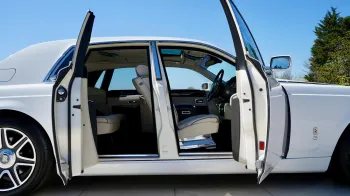 Right side view of White rolls-Royce Phantom with both front and rear coach doors open showing cream leather interior