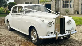 white Ribbons on a white Classic Rolls-Royce silver cloud with thin white wall tires, large front chrome grill.
