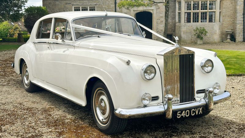 white Ribbons on a white Classic Rolls-Royce silver cloud with thin white wall tires, large front chrome grill.
