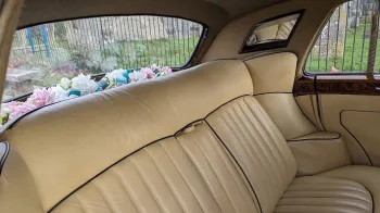 rear seats cream leather inside Bentley with vanity mirror and flowers on the rear parcel shelf