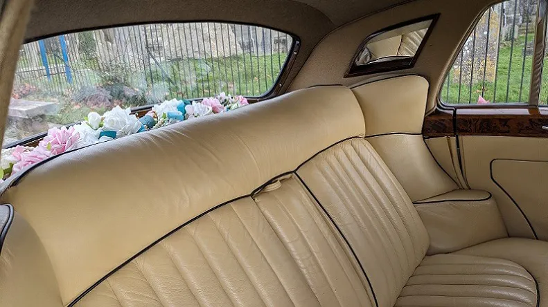 rear seats cream leather inside Bentley with vanity mirror and flowers on the rear parcel shelf