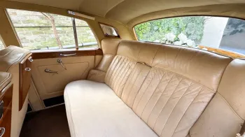 Interior photo of rear cream leather seats of cream Leather interior and wooden picnic table fitted in the back of the front passenger's seats