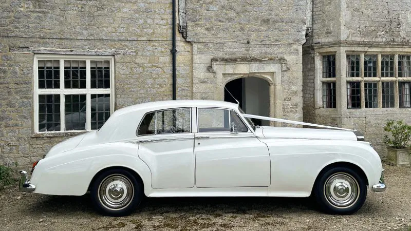 right side view of White Classic Rolls-Royce white thin white wall tires and wedding ribbons