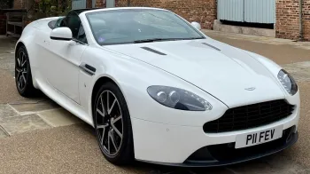 Front right side view of white Aston Martin Vantage with convertible roof open