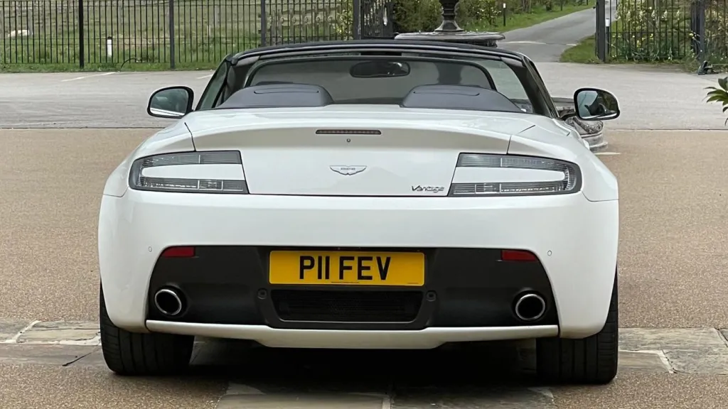 Full rear view of white Astn Martin Vantage with convertible roof open