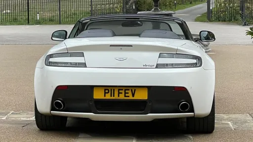 Full rear view of white Astn Martin Vantage with convertible roof open