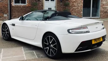 Left side view of White Aston Martinn Vantage with convertible soft top roof open