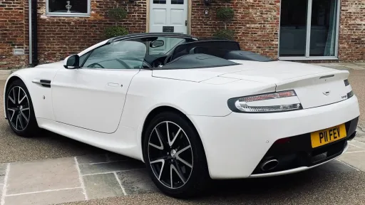 Left side view of White Aston Martinn Vantage with convertible soft top roof open