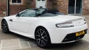 Left side view of White Aston Martinn Vantage with convertible soft top roof open