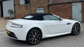 Right side view of white modern Aston Martin Vantage with black soft top roof closed