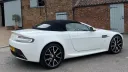 Right side view of white modern Aston Martin Vantage with black soft top roof closed