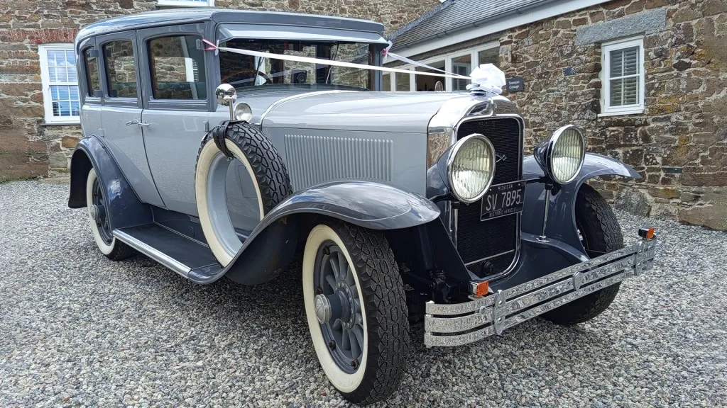 Two-tone silver with grey roof and wheel arches Vintage American Buick with spare tire on the side and decorated with white ribbons and bow