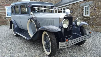 Two-tone silver with grey roof and wheel arches Vintage American Buick with spare tire on the side and decorated with white ribbons and bow
