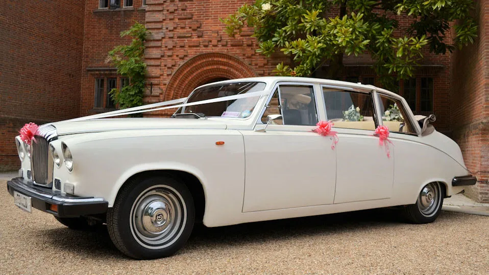 Classic Daimler Limousine with convertible landaulette style roof open decorated with white ribbons and dusty pink bows