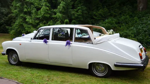 Classic convertible limousine with roof open and decorated with purple ribbons
