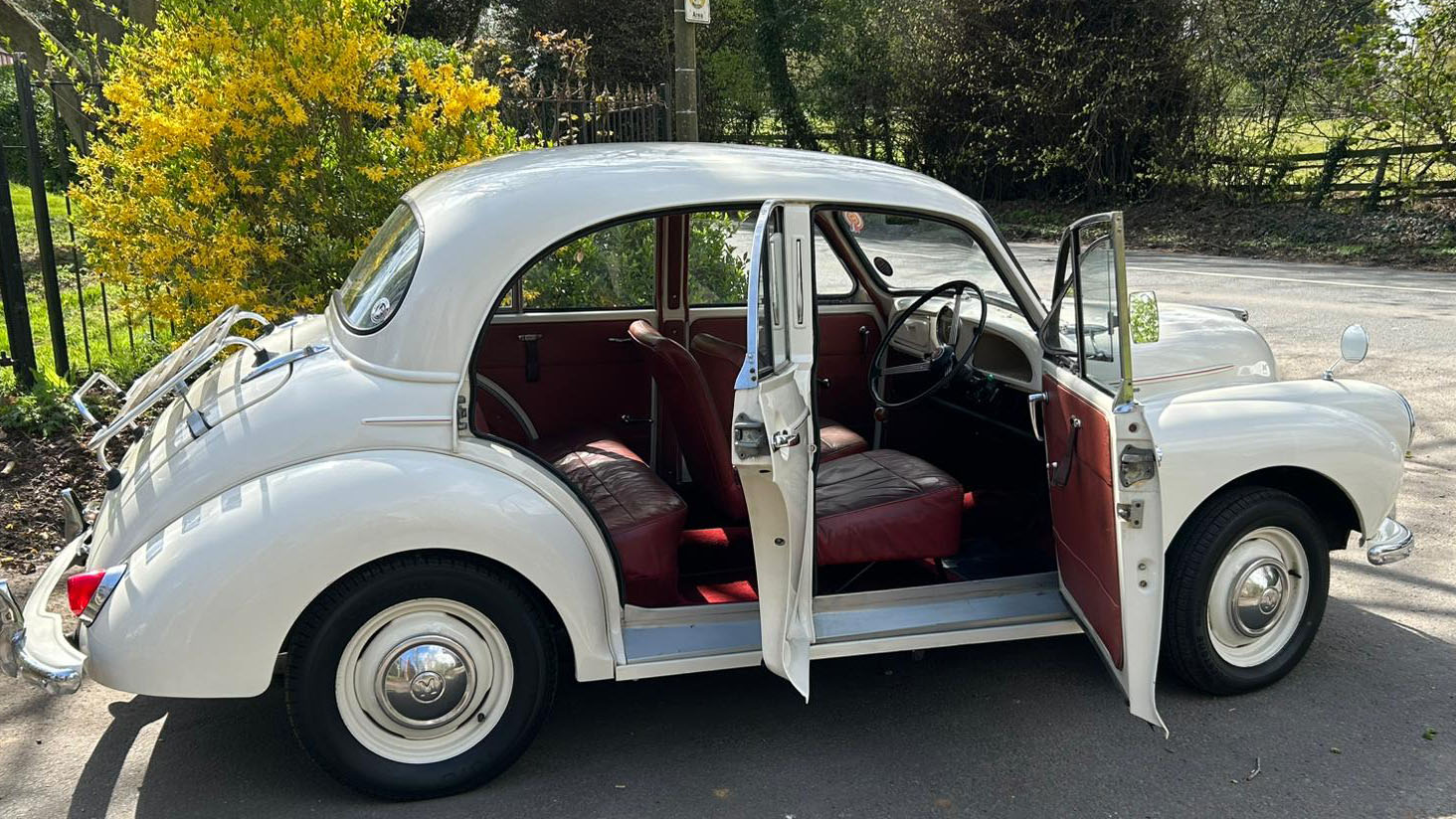 Righ side view classic Morris Minor with both doors open showing burgundy interior