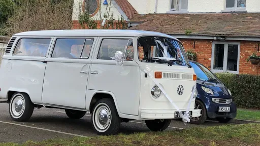 Right side view of a Classic VW Campervan dressed with white wedding ribbons