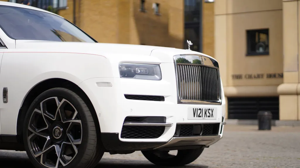 Front side view of White rolls-royce Cullinan with large Black and Silver alloy wheels and chrome front grill