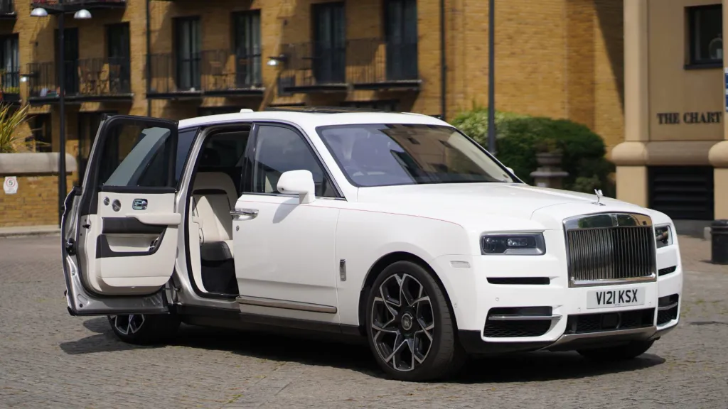 Right side view of a white Rolls-royce Cullinan with rear passenger door showing a cream leather interior