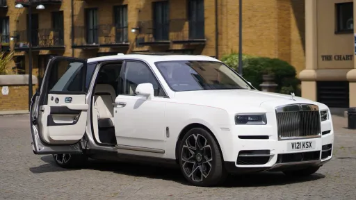 Right side view of a white Rolls-royce Cullinan with rear passenger door showing a cream leather interior
