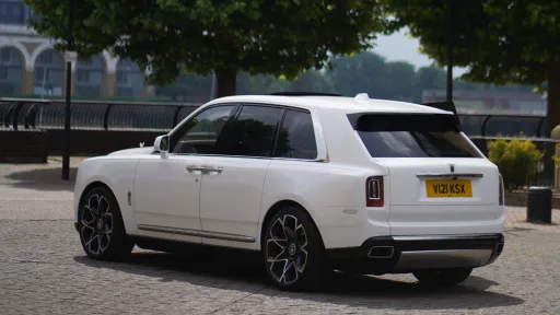 Rear left side view of a white Rolls-Royce cullinan with rear privacy windows
