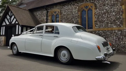 rear left view of a white Classic Rolls-Royce Silver Cloud parked in front of a wedding church.