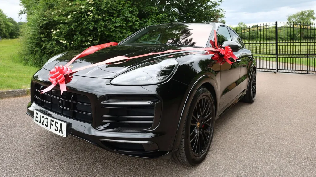 Black Porsche Cayenne GTS front left side view decorated with Red ribbons and bows