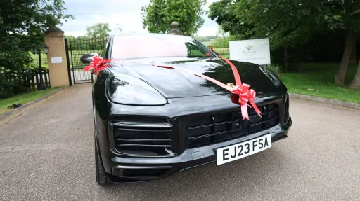 Black Porsche Cayenne GTS front view with bl;ack front grill and large Red bow at the  top of the grill