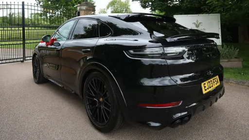Lefty side rear view Black Porsche Cayenne GTS with black privacy windows