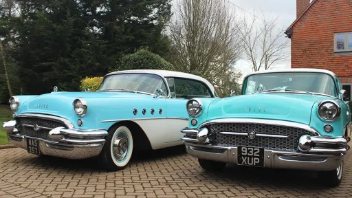 Two identical Turquoise Blue Buick with white roof and larged chrome bumper parked next to each other
