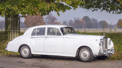 Right side view of Classic Rolls-Royce Silver Cloud in White with greenery in the background