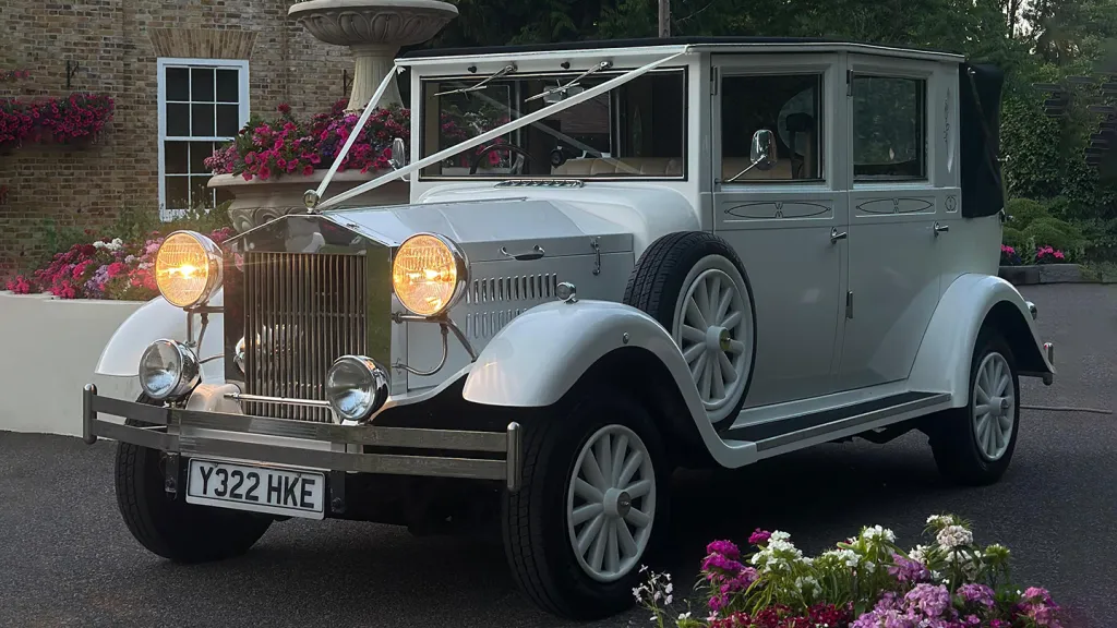 Front left view of vintage style imperial at dusck with front headlights on. The spare wheels aremounted on the side of the vehicle.