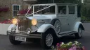 Front left view of vintage style imperial at dusck with front headlights on. The spare wheels aremounted on the side of the vehicle.