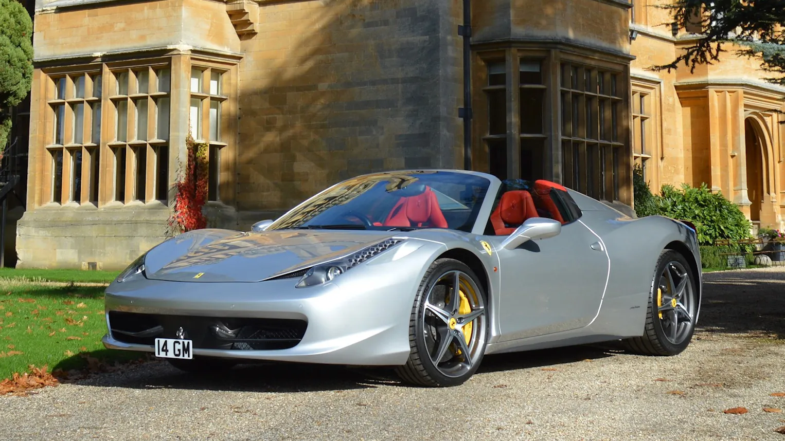 Light silver Ferrari parked in front of a wedding venue