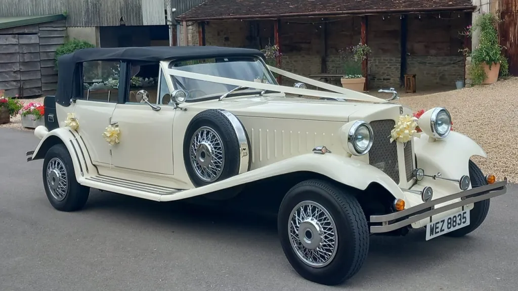 Front right view of Ivory Beauford with Black soft top roof up and white ribbons accross th front bonet
