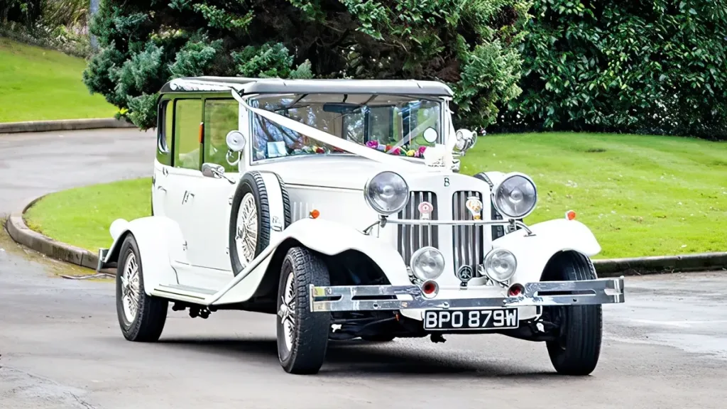 Vintage Beauford with white ribbons entering wedding venue