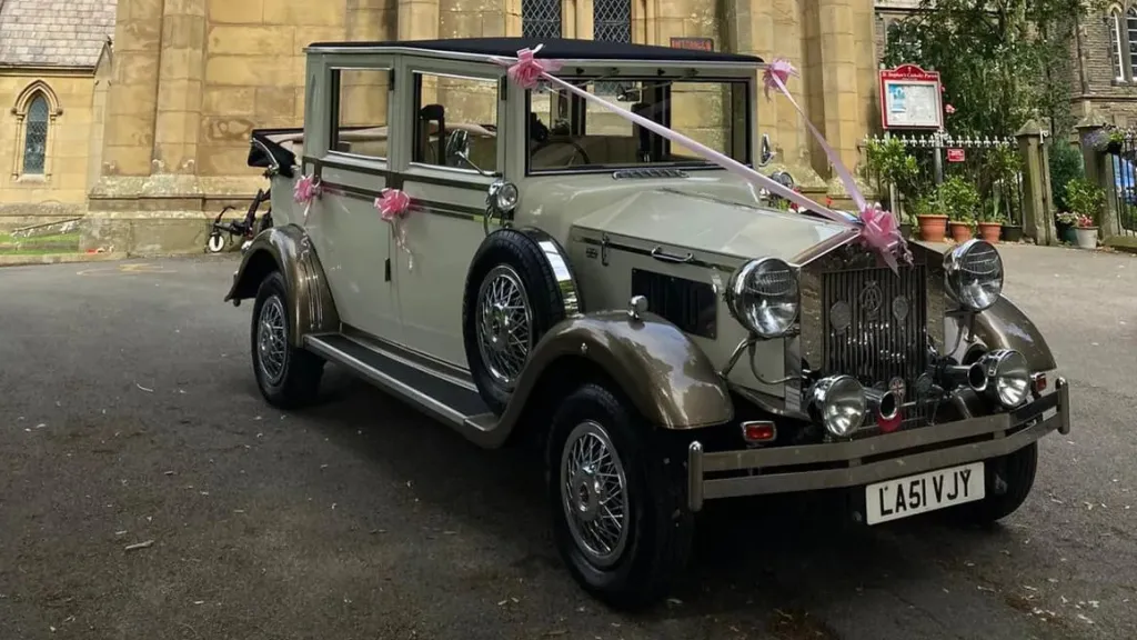 Imperial Viscount Landaulette in front of a church with convertible roof open decorated with light pink ribbons and bows on door handles