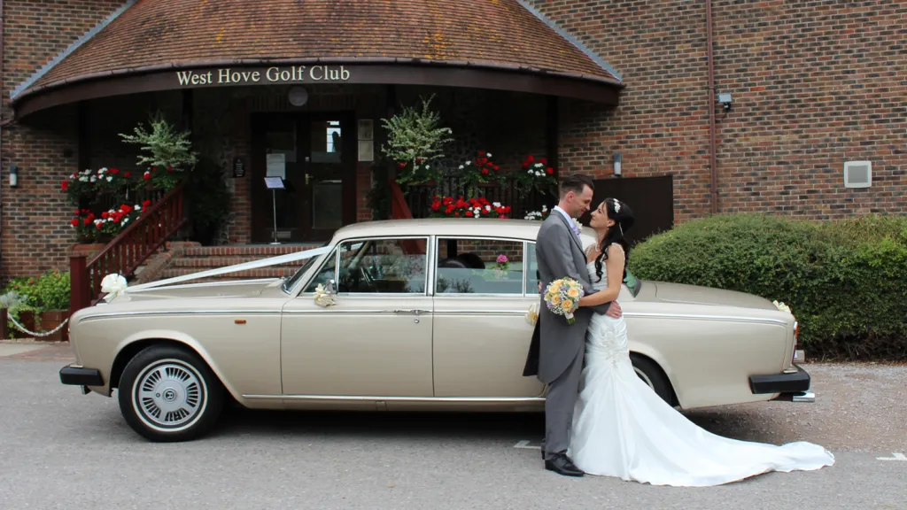 Bride and Groom holding each others next to a glod rolls-Royce silver shadow parked at a wedding venue in Sussex