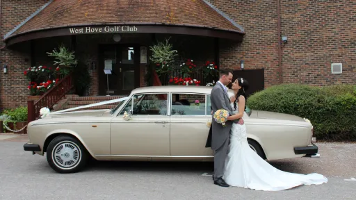 Bride and Groom holding each others next to a glod rolls-Royce silver shadow parked at a wedding venue in Sussex