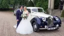 Bride and Groom standing in front of a Blue and Ivory vintage-style Royale Windsor